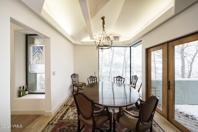 dining room featuring baseboards, lofted ceiling, wood finished floors, french doors, and a chandelier