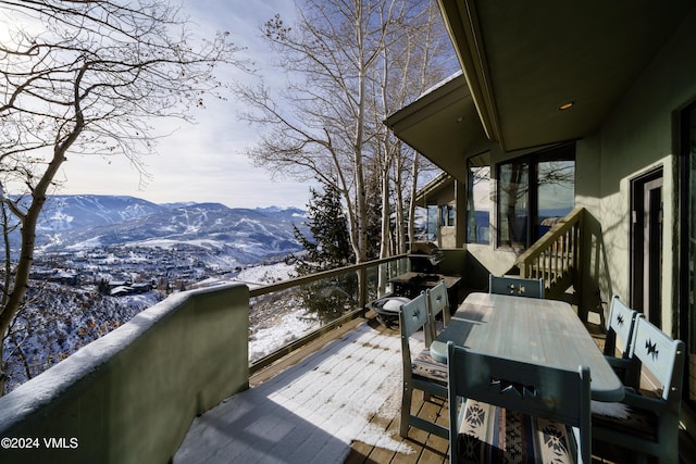 snow covered deck featuring outdoor dining space and a mountain view