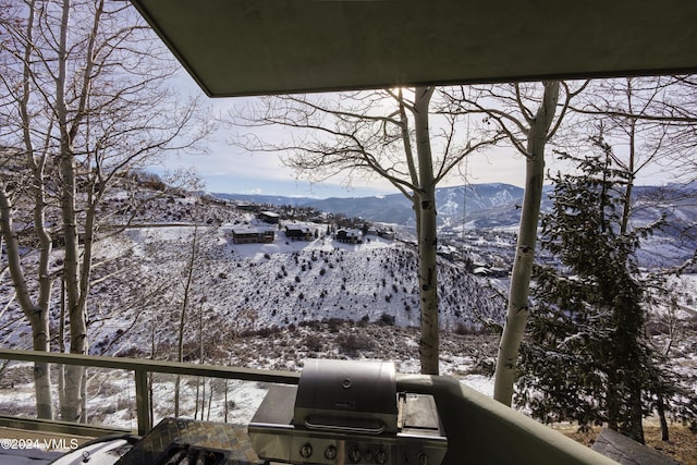 snow covered back of property with a mountain view and area for grilling