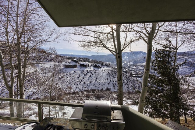 snow covered back of property featuring a mountain view and area for grilling