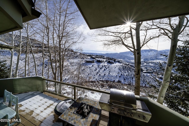 snow covered back of property with area for grilling and a mountain view