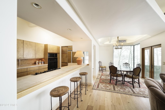 4747 Wildridge Rd, Avon, CO 81620 - interior space featuring an inviting chandelier, a kitchen breakfast bar, gas cooktop, a tray ceiling, and light wood-style flooring