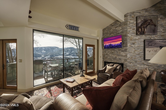 living room with lofted ceiling with beams and a stone fireplace