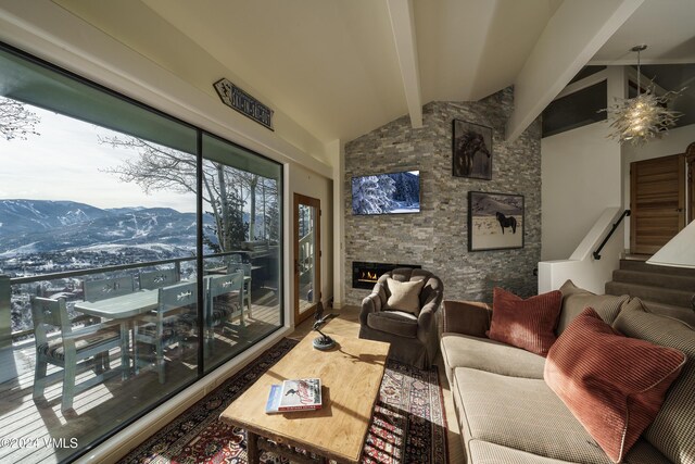 living area with wood finished floors, vaulted ceiling with beams, a stone fireplace, and stairs