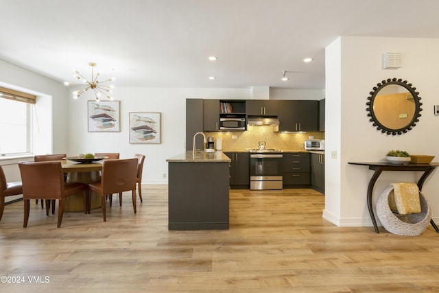 kitchen featuring sink, extractor fan, dark stone countertops, appliances with stainless steel finishes, and decorative backsplash