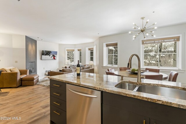 kitchen featuring sink, dishwasher, an inviting chandelier, light stone countertops, and light wood-type flooring