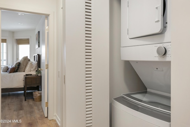 laundry room featuring hardwood / wood-style flooring and stacked washer / dryer