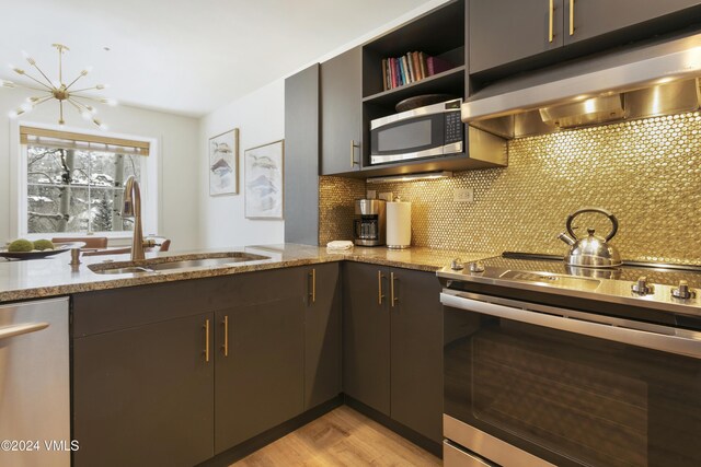 kitchen with sink, light stone counters, appliances with stainless steel finishes, light hardwood / wood-style floors, and backsplash