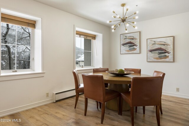 dining space with a baseboard radiator, a chandelier, and light hardwood / wood-style floors