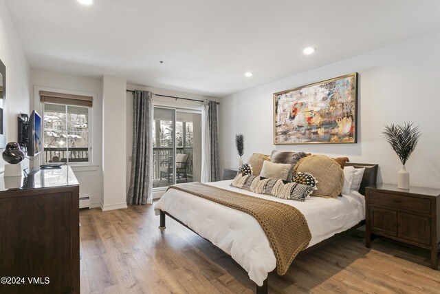 bedroom featuring a baseboard radiator, access to exterior, and light hardwood / wood-style floors