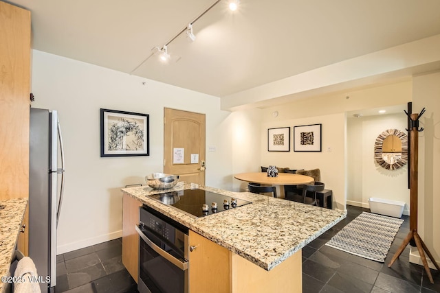 kitchen featuring baseboards, stainless steel appliances, light stone counters, and a center island