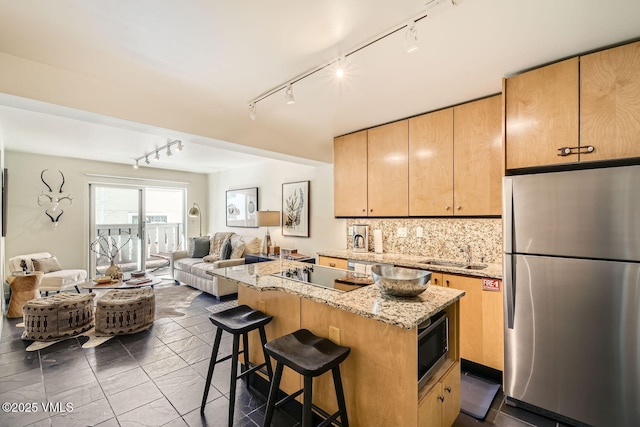 kitchen featuring light stone counters, open floor plan, appliances with stainless steel finishes, backsplash, and a center island