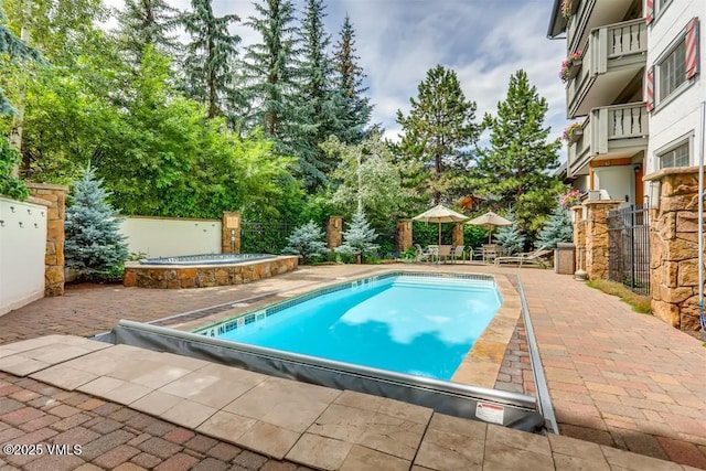 community pool featuring a patio, a community hot tub, and a fenced backyard