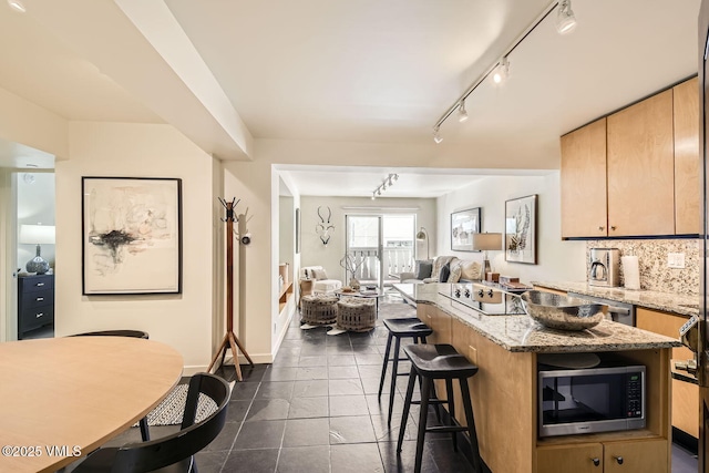 kitchen with a center island, stainless steel microwave, backsplash, open floor plan, and a kitchen breakfast bar