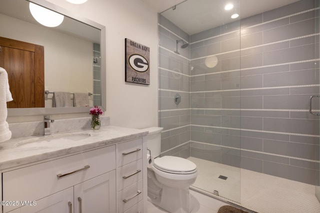 full bathroom with tile patterned flooring, toilet, tiled shower, and vanity