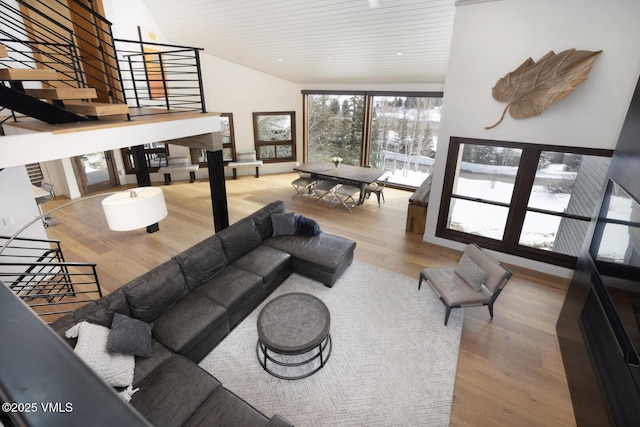 living room featuring stairs, wood finished floors, and high vaulted ceiling