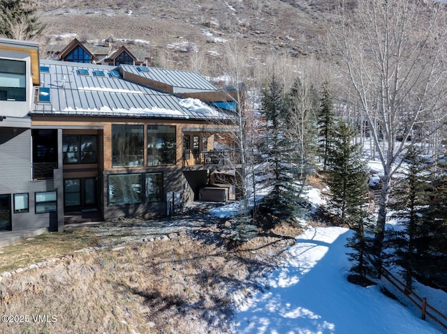 snow covered house with metal roof and a standing seam roof