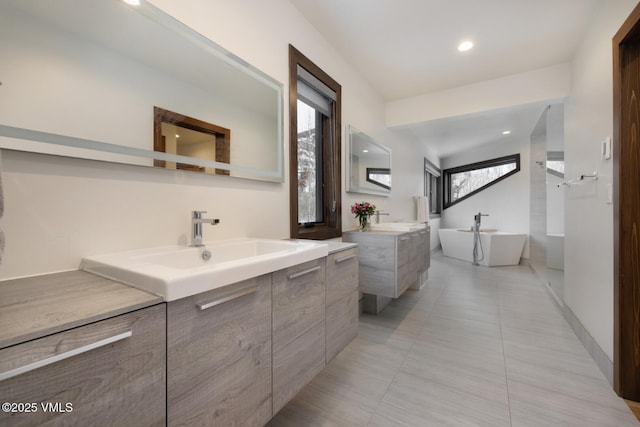 full bathroom with a freestanding tub, two vanities, recessed lighting, a sink, and tile patterned flooring