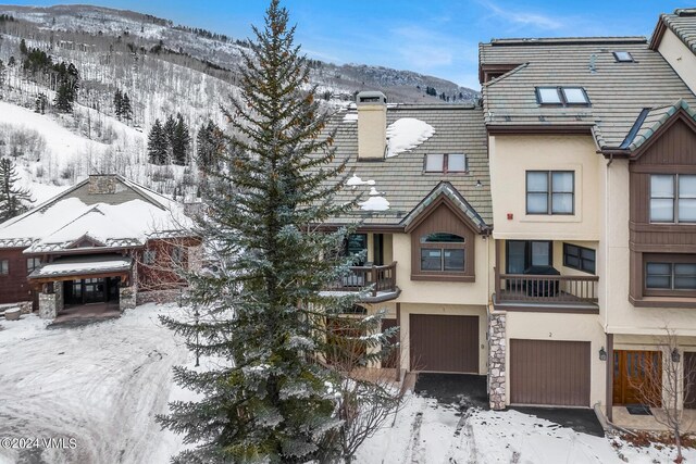 view of property featuring stucco siding, a garage, a mountain view, and a chimney