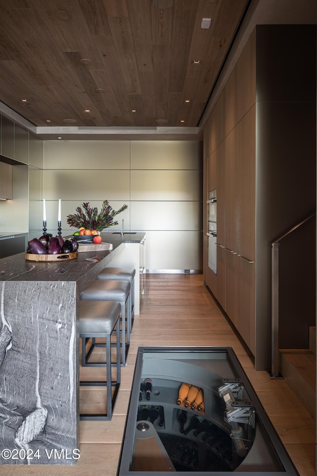 100 Vail Rd, Vail, CO 81657 - kitchen with wood ceiling, dark stone counters, double wall oven, light wood finished floors, and modern cabinets