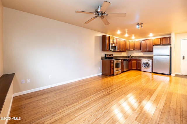 kitchen with washer / dryer, ceiling fan, light wood-style floors, appliances with stainless steel finishes, and dark countertops