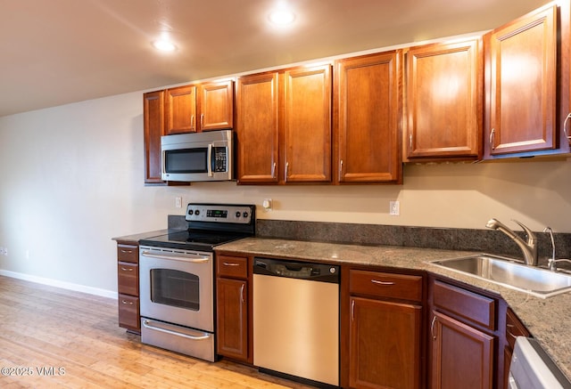 kitchen with baseboards, recessed lighting, appliances with stainless steel finishes, light wood-style floors, and a sink