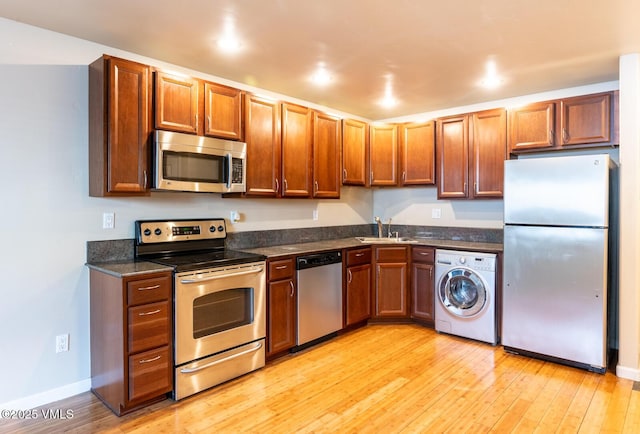 kitchen featuring a sink, washer / clothes dryer, appliances with stainless steel finishes, light wood finished floors, and baseboards