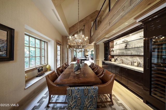 17 Chateau Ln Unit 501, Beaver Creek, CO 81620 - dining area with a chandelier, light wood-style floors, high vaulted ceiling, and a dry bar