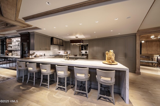 17 Chateau Ln Unit 501, Beaver Creek, CO 81620 - kitchen featuring stainless steel stovetop, a breakfast bar area, light stone counters, light wood-style flooring, and recessed lighting