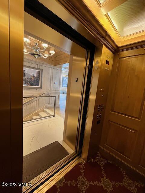 17 Chateau Ln Unit 501, Beaver Creek, CO 81620 - elevator with ornamental molding, a chandelier, and wooden walls