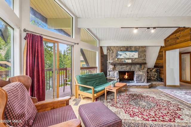 sitting room with wood ceiling, a stone fireplace, lofted ceiling with beams, and rail lighting