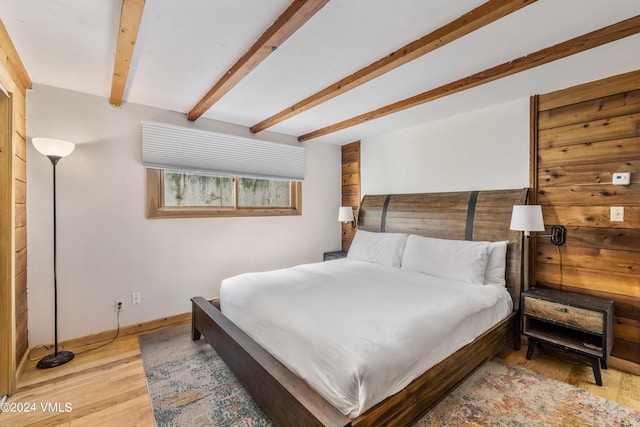 bedroom featuring beamed ceiling and light wood-type flooring