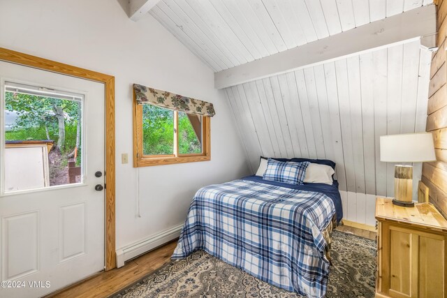 bedroom with lofted ceiling with beams, hardwood / wood-style flooring, baseboard heating, and multiple windows