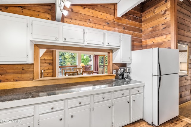 kitchen featuring white cabinetry, light wood-type flooring, wood walls, and white fridge