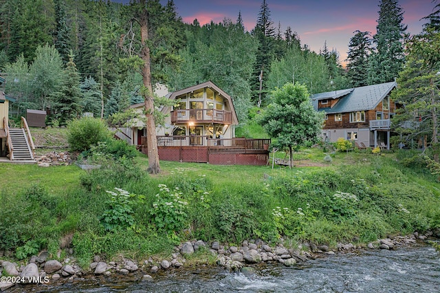 yard at dusk with a wooden deck and a sunroom