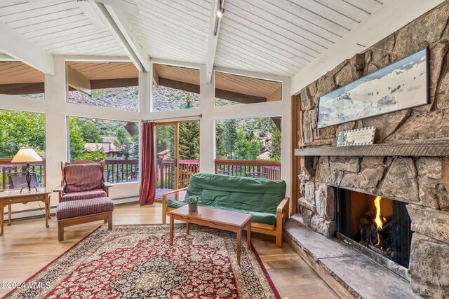 sunroom / solarium with wood ceiling, a healthy amount of sunlight, a stone fireplace, and vaulted ceiling with beams