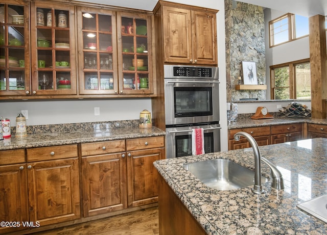 0017 Harvester Ct, Eagle, CO 81631 - kitchen featuring stainless steel double oven, a sink, glass insert cabinets, and brown cabinets