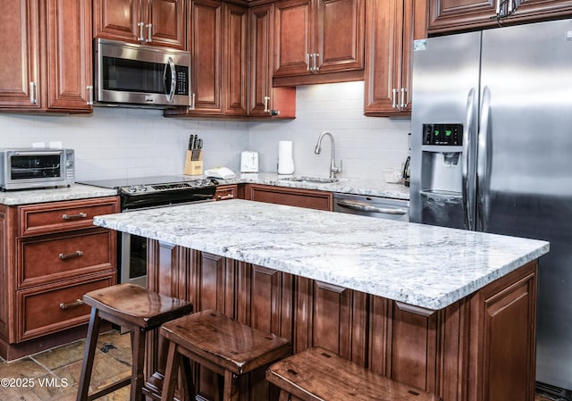 kitchen with a sink, light stone counters, appliances with stainless steel finishes, and a toaster