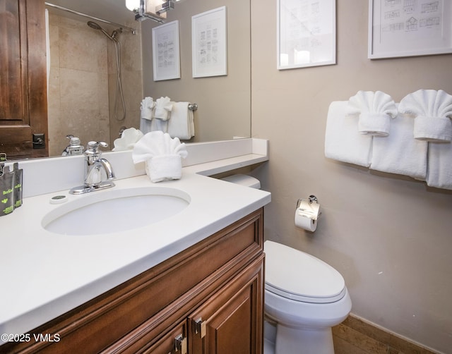 bathroom featuring a tile shower, toilet, and vanity