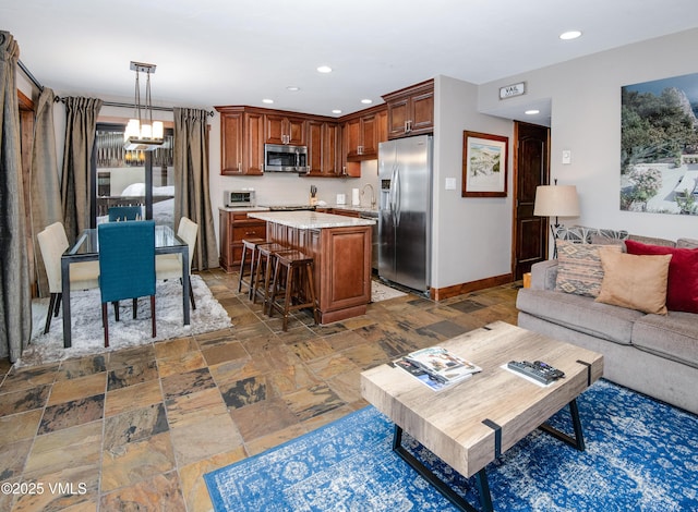 living area with stone tile floors, baseboards, an inviting chandelier, a toaster, and recessed lighting