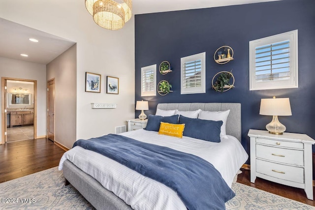 bedroom featuring dark wood-type flooring, an inviting chandelier, and ensuite bath