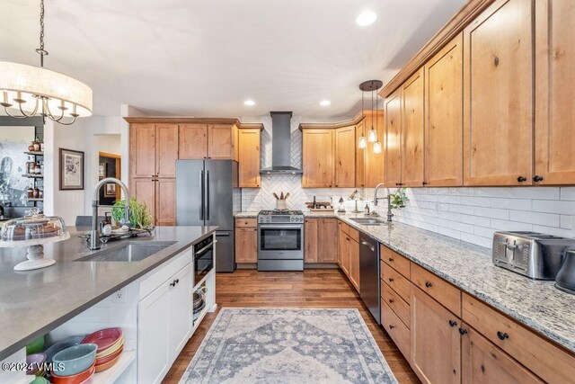 kitchen featuring sink, decorative light fixtures, wall chimney exhaust hood, and appliances with stainless steel finishes