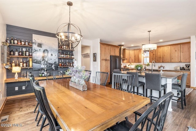 dining area with hardwood / wood-style floors, wet bar, and a chandelier