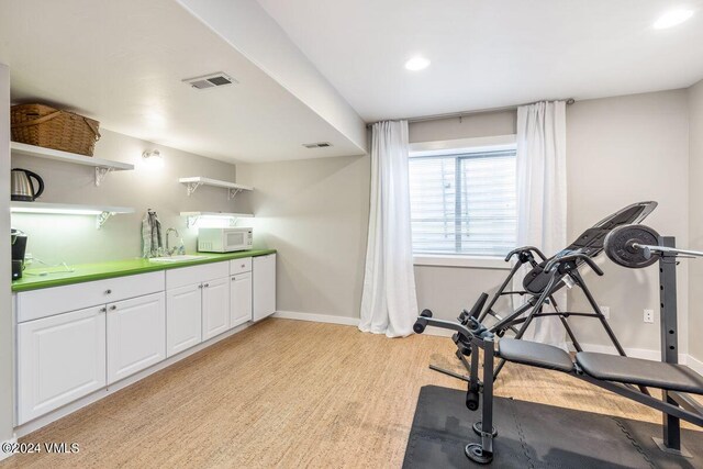 exercise area featuring sink and light hardwood / wood-style flooring