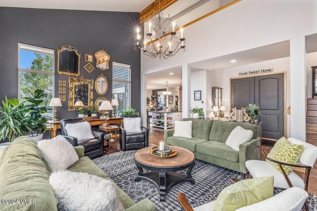 living room featuring hardwood / wood-style flooring, a towering ceiling, an inviting chandelier, and beamed ceiling