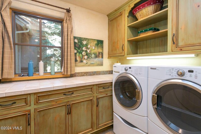 laundry area featuring a wealth of natural light, cabinets, and washing machine and clothes dryer