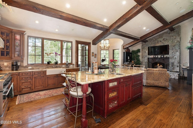 kitchen featuring a spacious island, high end range, a breakfast bar, and sink