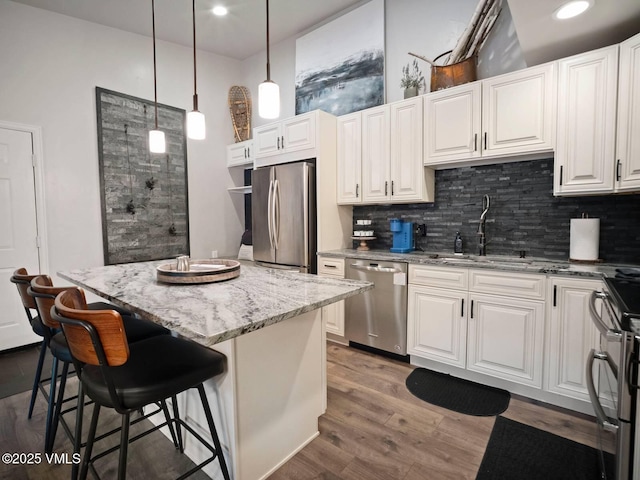 1061 W Beaver Creek Blvd Unit F-203, Avon, CO 81620 - kitchen featuring appliances with stainless steel finishes, a sink, decorative backsplash, a center island, and light stone counters