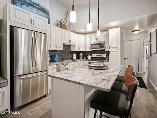 1061 W Beaver Creek Blvd Unit F-203, Avon, CO 81620 - kitchen with appliances with stainless steel finishes, light wood-type flooring, white cabinetry, a sink, and a towering ceiling