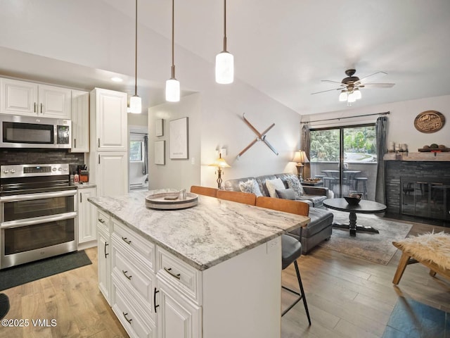 1061 W Beaver Creek Blvd Unit F-203, Avon, CO 81620 - kitchen with appliances with stainless steel finishes, ceiling fan, a breakfast bar area, open floor plan, and light wood finished floors